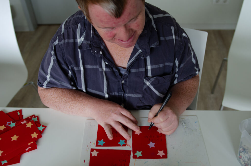 Mann mit Down-Syndrom bastelt Weihnachtskarten